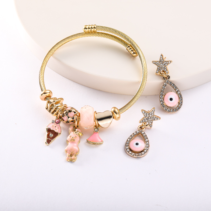 pulsera dorada con charms y aretes de ojito