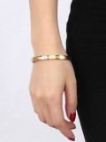 Brazalete de titanio con diseño de tres circonitas chapado en oro que combina con todo