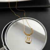 Collar chapado en oro de 18 quilates con incrustaciones de concha y acero de titanio con letras de estilo clásico básico