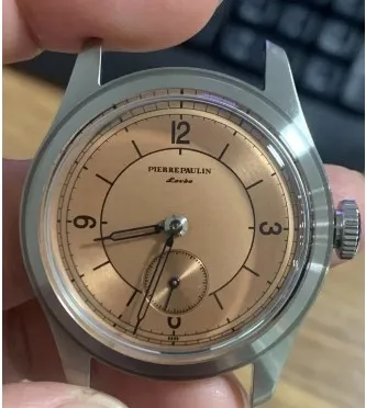 Pierre Paulin salmon sector mechanical watch held in a hand showing its curved crystal and small-seconds subdial