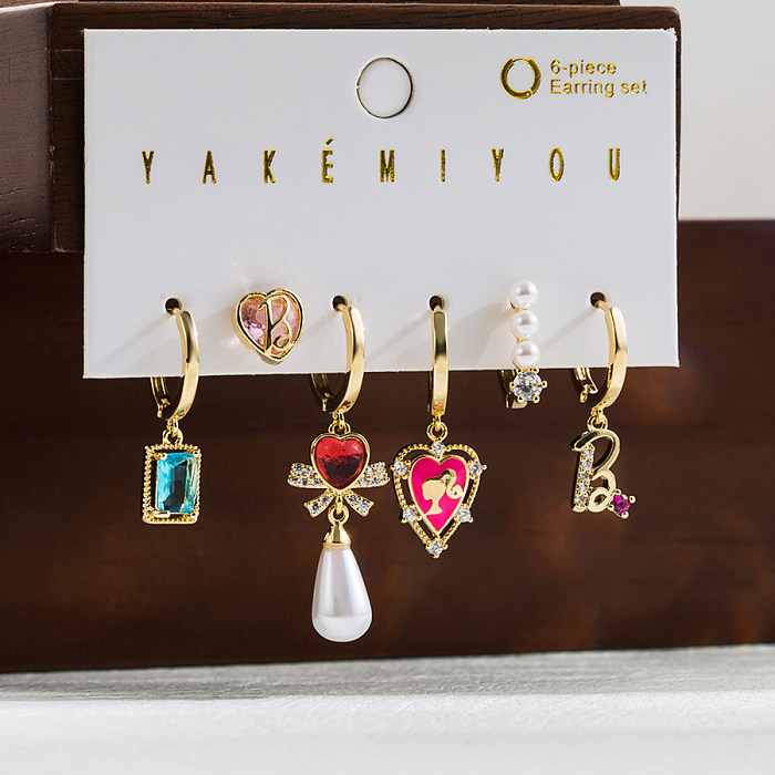 Pendientes colgantes chapados en oro de 14K con incrustaciones de esmalte de cobre y nudo de lazo de Barbie en forma de corazón bonito de Yakemiyou