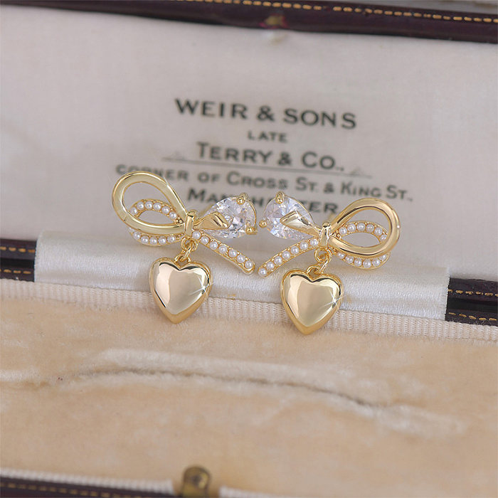 1 paire de clous d'oreilles plaqués or 14 carats avec perles artificielles en cuivre et zircone, style féerique, style français, style simple, forme de cœur, nœud papillon, incrustation