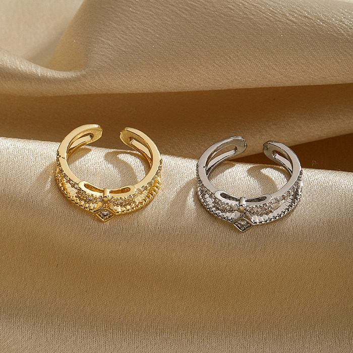 Pendeln Sie glänzende offene Ringe mit Schleife und Knoten aus Kupfer und Metall mit ausgehöhltem Inlay und Zirkon