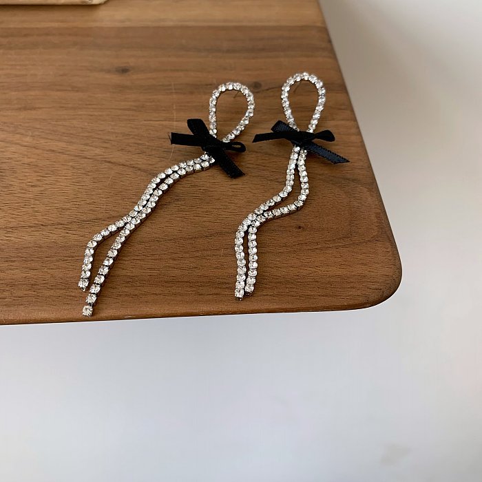 1 paire de boucles d'oreilles pendantes avec nœud papillon brillant, incrustation de strass en cuivre plaqué argent
