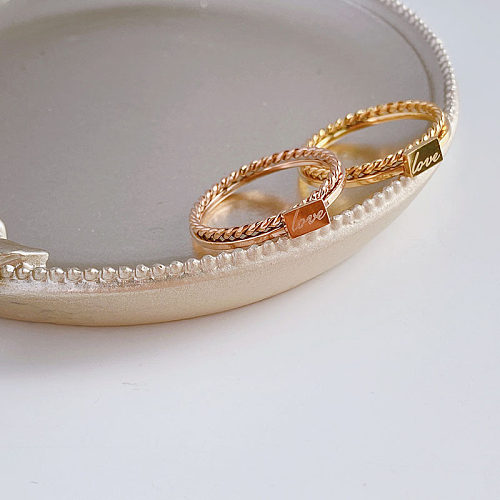Anéis banhados a ouro com chapeamento de aço de titânio com letra de estilo simples
