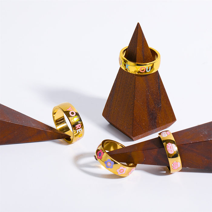Anéis de esmalte de aço de titânio com flor de letra fofa