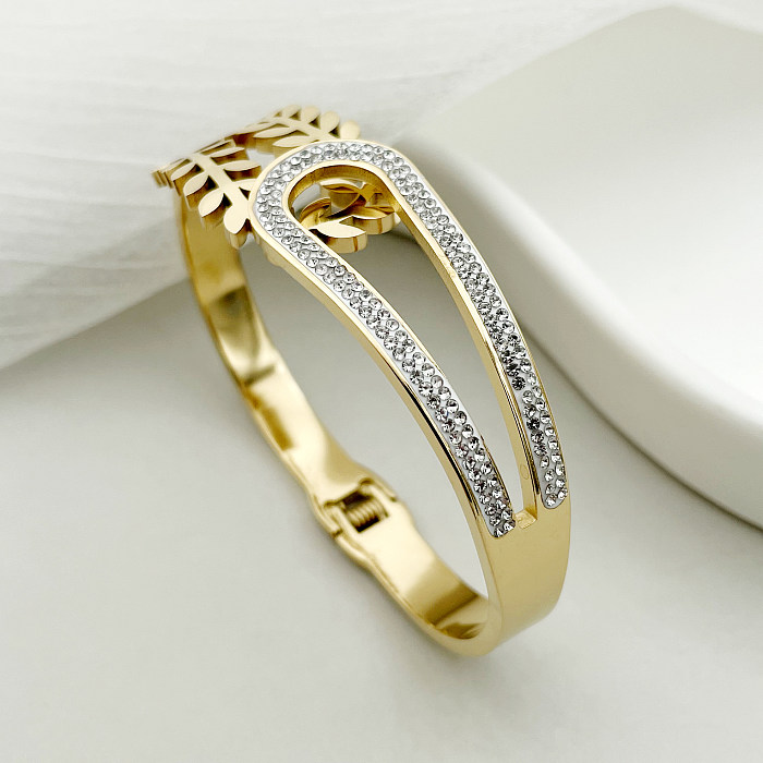 Brazalete chapado en oro con incrustaciones de diamantes de imitación y hebilla de acero inoxidable y titanio con hojas elegantes