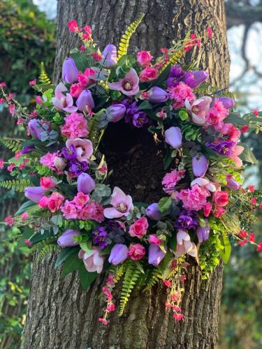Handmade spring faux flower door wreath in pinks, purples and green.