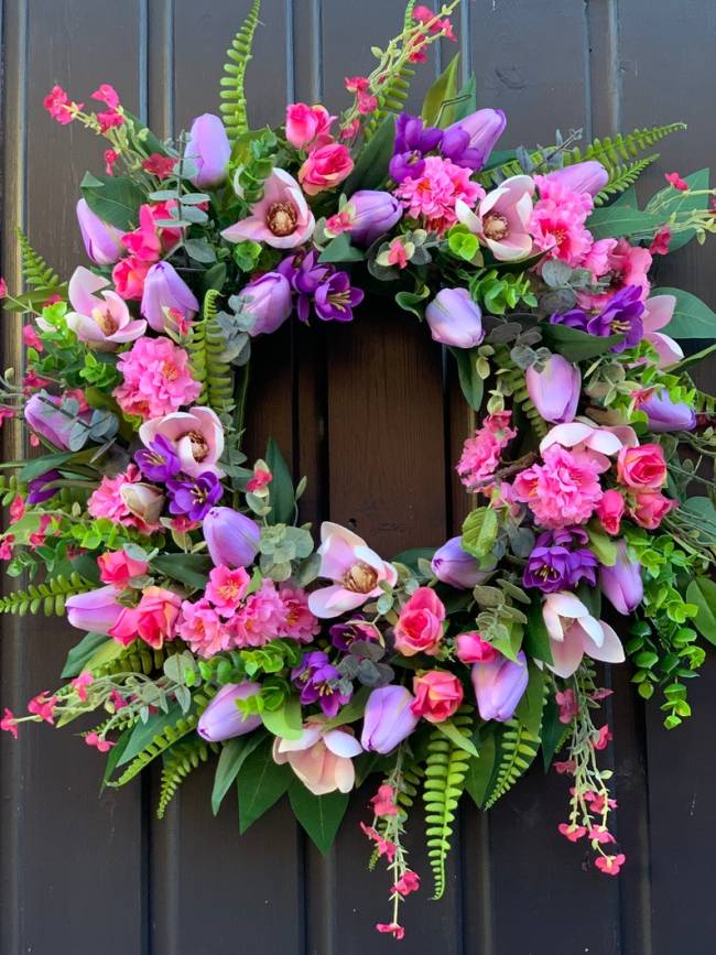 Handmade spring faux flower door wreath in pinks, purples and green.