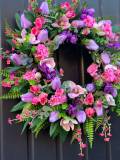 Handmade spring faux flower door wreath in pinks, purples and green.