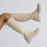 Small white boots with thick soles and high shafts are thinner than knees