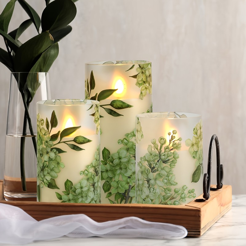 A set of 3 flameless candles, flickering LED pillar candles, with a 10-button remote control. They feature a green floral theme, are suitable for spring and summer, and can be used on the dining tables at wedding venues