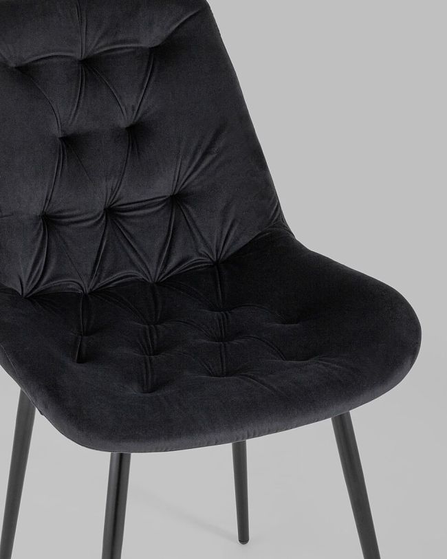 Black velvet tufted dining chair with a curved back and sleek metal legs